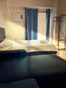 une chambre avec deux lits et une fenêtre avec des rideaux bleus dans l'établissement 8 Adriatico Homestay - S, à Manille