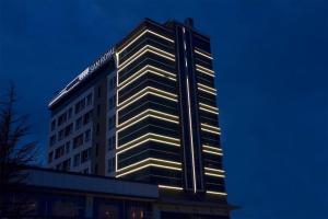 a tall building with lights on it at night at Sam Royal Hotel in Eskisehir