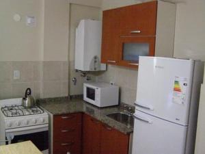 cocina con nevera blanca y microondas en Apartamento Edificio Atlantis I en Villa Carlos Paz