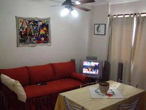 un soggiorno con divano rosso e TV di Apartamento Edificio Atlantis I a Villa Carlos Paz