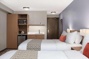 a hotel room with two beds and a kitchen at Microtel Inn & Suites by Wyndham Kirkland Lake in Kirkland Lake