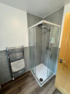 a shower with a glass door in a room at Inchcruin Apartment - Macaulay Letting in Bonhill