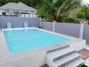 una piscina accanto a una recinzione bianca di Haimara staycation, 1 house & 3 cabin with pool hulu langat, for small event a Hulu Langat