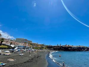 a beach with people on the sand and the water at Blue Garden - cozy apartment with Atlantic views in Puerto de Santiago