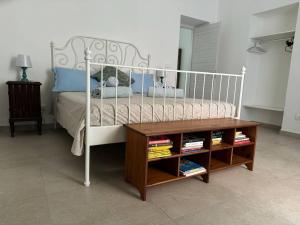 a bedroom with a white bed and a wooden table at Casa Ortensia in Santa Teresa di Riva