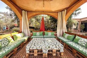 a porch with green couches and a table at DAR SMAWAR top piscine chauffée 15mn centre ville in El Caïd Omar