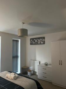 a white bedroom with a bed and a dresser at X marina breeze x in Swansea