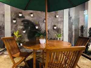 a wooden table with chairs and an umbrella at Robiu Bed & Breakfast in Banyuwangi