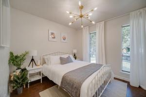 a white bedroom with a bed and a chandelier at Stunning 4BR 2BA Hot Tub Cozy Holiday Home in Plano in Plano