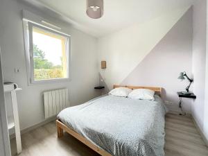 una camera da letto con un letto e una finestra di Sweet Omaha Belle maison récente lumineuse et cosy bien équipée jardin clos 15 mn à pied plage Omaha Beach et proche de Bayeux & Port en Bessin a Saint-Laurent-sur-Mer