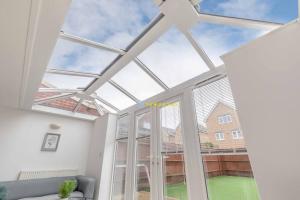 a conservatory with a large window and a couch at Modern Home - Slough, Heathrow, Pinewood - Parking in Langley Marish