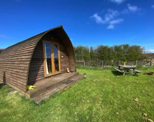 una piccola cabina in un campo con tavolo da picnic di Greenley Croft Glamping by Wigwam a Crovie