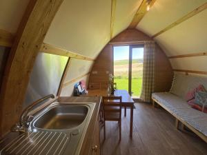 una cucina con lavandino e tavolo in una stanza di Greenley Croft Glamping by Wigwam a Crovie Altre 4 foto