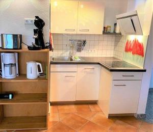 eine kleine Küche mit weißen Schränken und einer Spüle in der Unterkunft Zeesenhaus 06 in Ostseebad Sellin