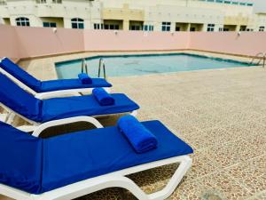 a pool with blue lounge chairs next to a swimming pool at Fortune Plaza Hotel, Dubai Airport in Dubai