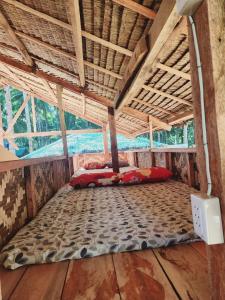 a bed in the middle of a room with a roof at Kubo ni Apple in Tagbina
