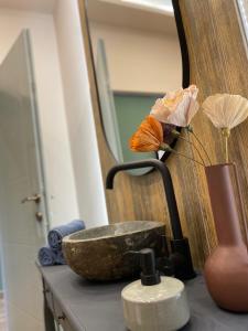 eine Arbeitsplatte mit einem Waschbecken und einer Vase mit Blumen in der Unterkunft The Loft Apartman Szeged in Szeged + 25 Fotos