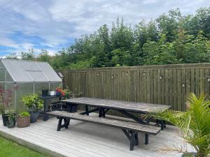 a wooden deck with a picnic table and a greenhouse at Presthusvegen in Trondheim