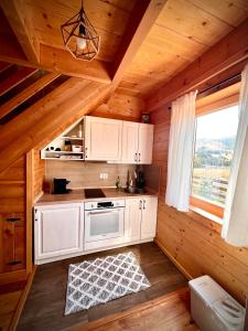 a kitchen with white cabinets in a wooden cabin at Starry Sky Zlatibor in Krajevi