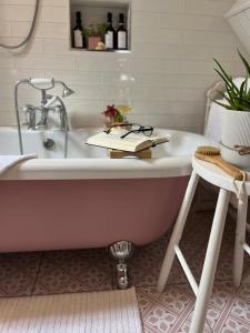 ein Badezimmer mit einer Badewanne mit einem Buch darauf in der Unterkunft The Pink Cottage upstairs suite & Garden Summer Room in Whitehead + 70 Fotos