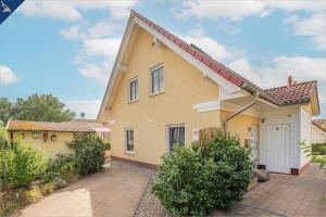 ein gelbes Haus mit weißer Tür in der Unterkunft Heimathafen An Seen & Meer in Korswandt