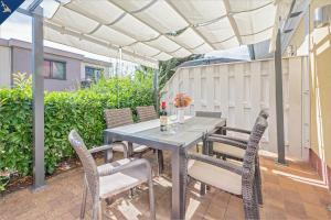 eine Terrasse mit Tisch und Stühlen unter einer weißen Pergola in der Unterkunft Heimathafen An Seen & Meer in Korswandt