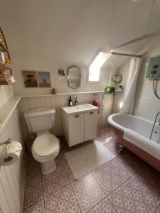 ein Badezimmer mit Toilette, Badewanne und Waschbecken in der Unterkunft The Pink Cottage upstairs suite & Garden Summer Room in Whitehead