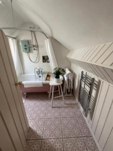 ein Bad im Dachgeschoss mit einer Badewanne und einem Waschbecken in der Unterkunft The Pink Cottage upstairs suite & Garden Summer Room in Whitehead