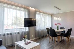 a living room with a table and chairs and a tv at Centrinė aikštė in Nida