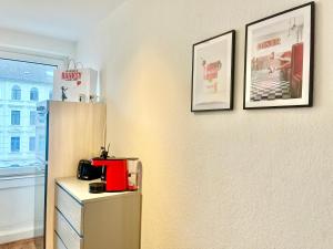 a kitchen with a refrigerator and two pictures on the wall at Banksy Apartment - Art & Fun mit 2 Balkonen - 6 Betten in Hannover +10 photos