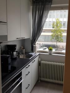 una cucina con mobili bianchi e una grande finestra di Kotimaailma Apartments - 1BR in city center of Turku a Turku