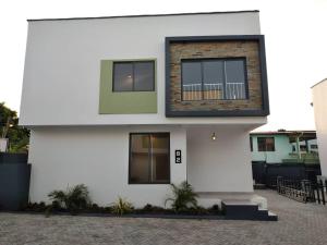 a white house with two windows and a courtyard at 82 Avenue D West, North Legon in North Legon