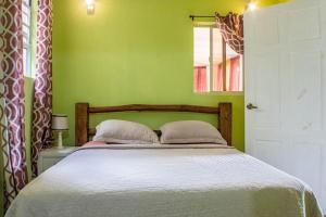 a bedroom with a bed with a green wall at Montete Cottage Hilltop Villa with Beautiful Estate Garden in Choiseul