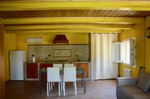 eine Küche mit einem Tisch und einigen weißen Stühlen in der Unterkunft B&B Ca' Viola in San Pietro in Trento