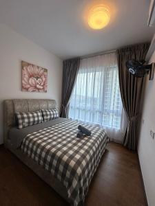 a bedroom with a bed with a plaid blanket and a window at Central Park 2 Bedrooms in Johor Bahru