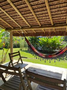 un hamac, une chaise et un banc sur une terrasse dans l'établissement Vila do Teteco Ecopousada, à Parati