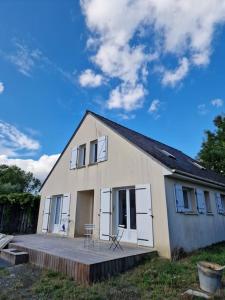 a small white house with a deck in front of it at pavillon en pleine nature in Brains-sur-Gée
