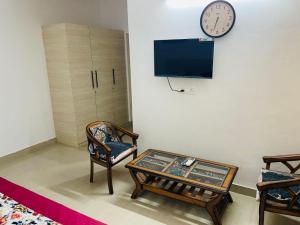 a living room with a table and a clock on the wall at VisitorStayInn in Vrindāvan +3 photos