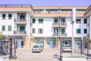 a white building with a car parked in front of it at Residence del mare in Ardea