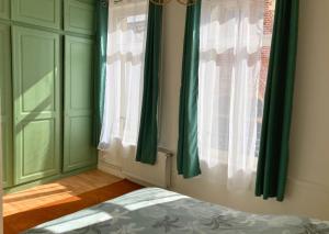 una camera da letto con tende verdi, un letto e una finestra di Le Bohemian Chic - 4 chambres en hypercentre de Saint-Omer, idéal pour les groupes a Saint-Omer