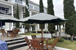 a table and chairs with an umbrella on a patio at Green Hero Darajat Hotel in Darajat