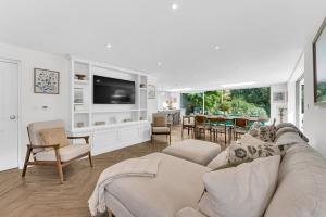 un salon avec un canapé et une télévision dans l'établissement Garden Cottage, à Cuddington