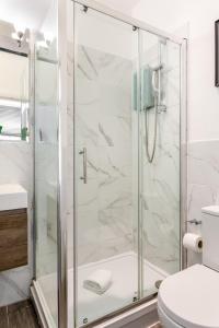 a shower with a glass door in a bathroom at Cozy Kingfisher - 2-Bed Bungalow in Brighton near the Beach With Free WiFi & Terrace by Kozmo Properties in Brighton & Hove +12 photos