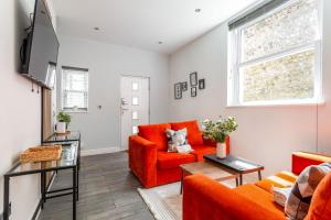 a living room with orange furniture and a tv at Seabreeze Hideaway By Kozmo - Cozy 2-Bed Bungalow in Brighton near the Beach With Free WiFi & Terrace by Kozmo Properties in Brighton & Hove