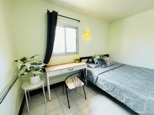 a bedroom with a bed and a desk and a window at KLApartment in Ban Bang Chak