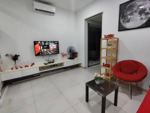 ein Wohnzimmer mit einem TV und einem roten Stuhl in der Unterkunft Private Cinema and Jacuzzi at Pertama Residency in Kuala Lumpur