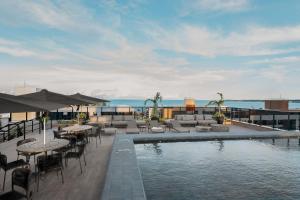 a swimming pool with tables and chairs next to the ocean at Way Tambaú #J2 - Triplo deluxe por Carpediem in Tambaú