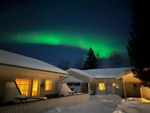 Una aurora brilla en el cielo sobre una casa en Lomavekarit Apartments, en Rovaniemi
