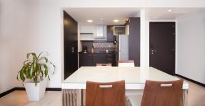 a kitchen with a white table and wooden chairs at Suite 14 Bellini I, Puerto Santa Ana, Guayaquil in Guayaquil