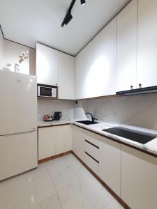 a white kitchen with white cabinets and a sink at Riviera apartment for 6 persons in Almaty +6 photos